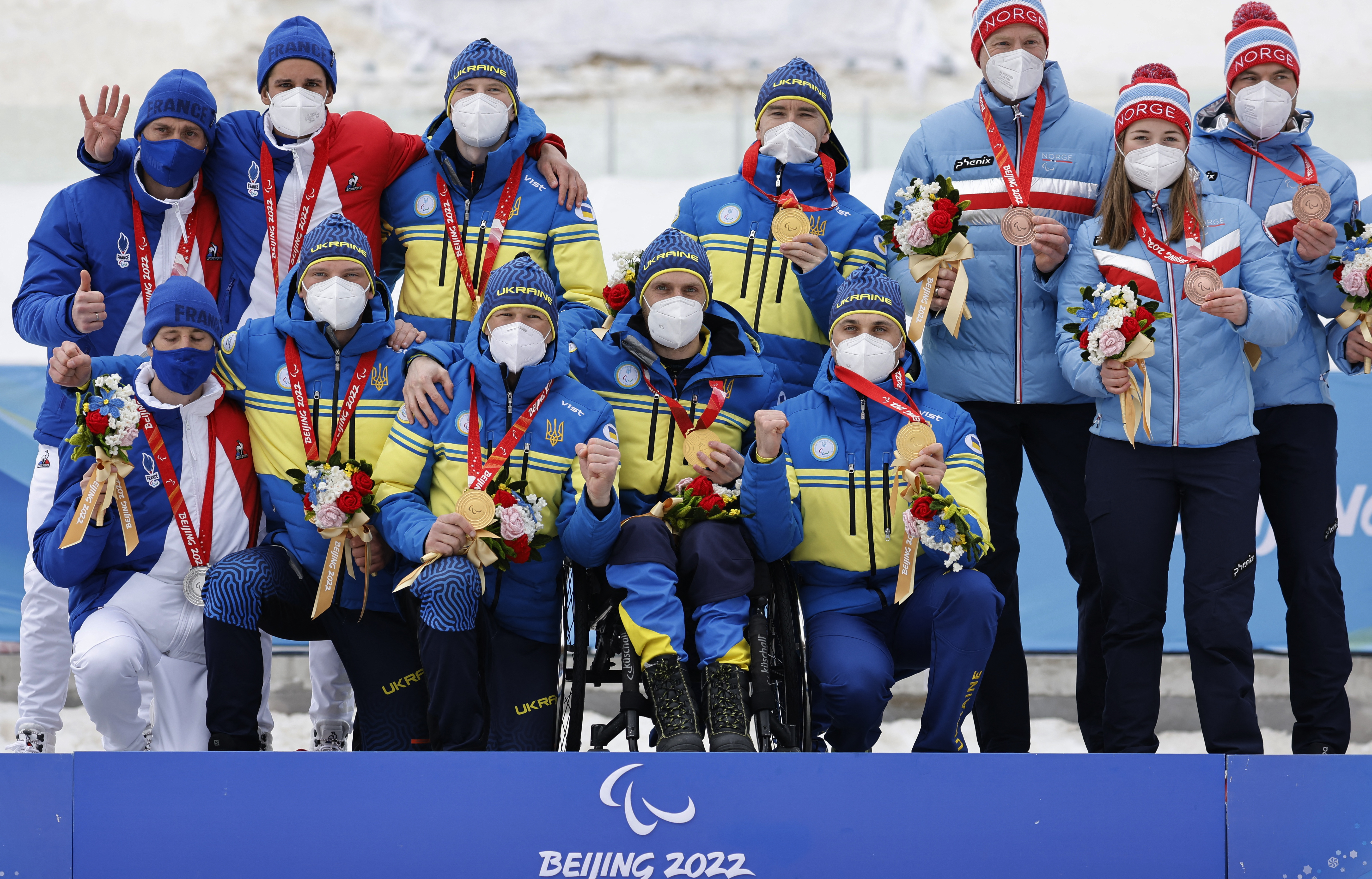 Beijing 2022 Winter Paralympic Games - Para Cross-Country Skiing - Open Relay 4 x 2.5km - National Biathlon Centre, Zhangjiakou, China - March 13, 2022. Silver medallists Benjamin Daviet of France, Anthony Chalencon of France and guide Brice Ottonello of France, Gold medallists Dmytro Suiarko of Ukraine with guide Oleksandr Nikonovych of Ukraine, Grygorii Vovchynskyi of Ukraine, Vasyl Kravchuk of Ukraine and Anatolii Kovalevskyi of Ukraine with guide Oleksandr Mukshyn of Ukraine and Bronze medallists Kjartan Haugen of Norway, Vilde Nilsen of Norway and Thomas Oxaal of Norway with guide Ole-Martin Lid of Norway pose during the medal ceremony. REUTERS/Issei Kato