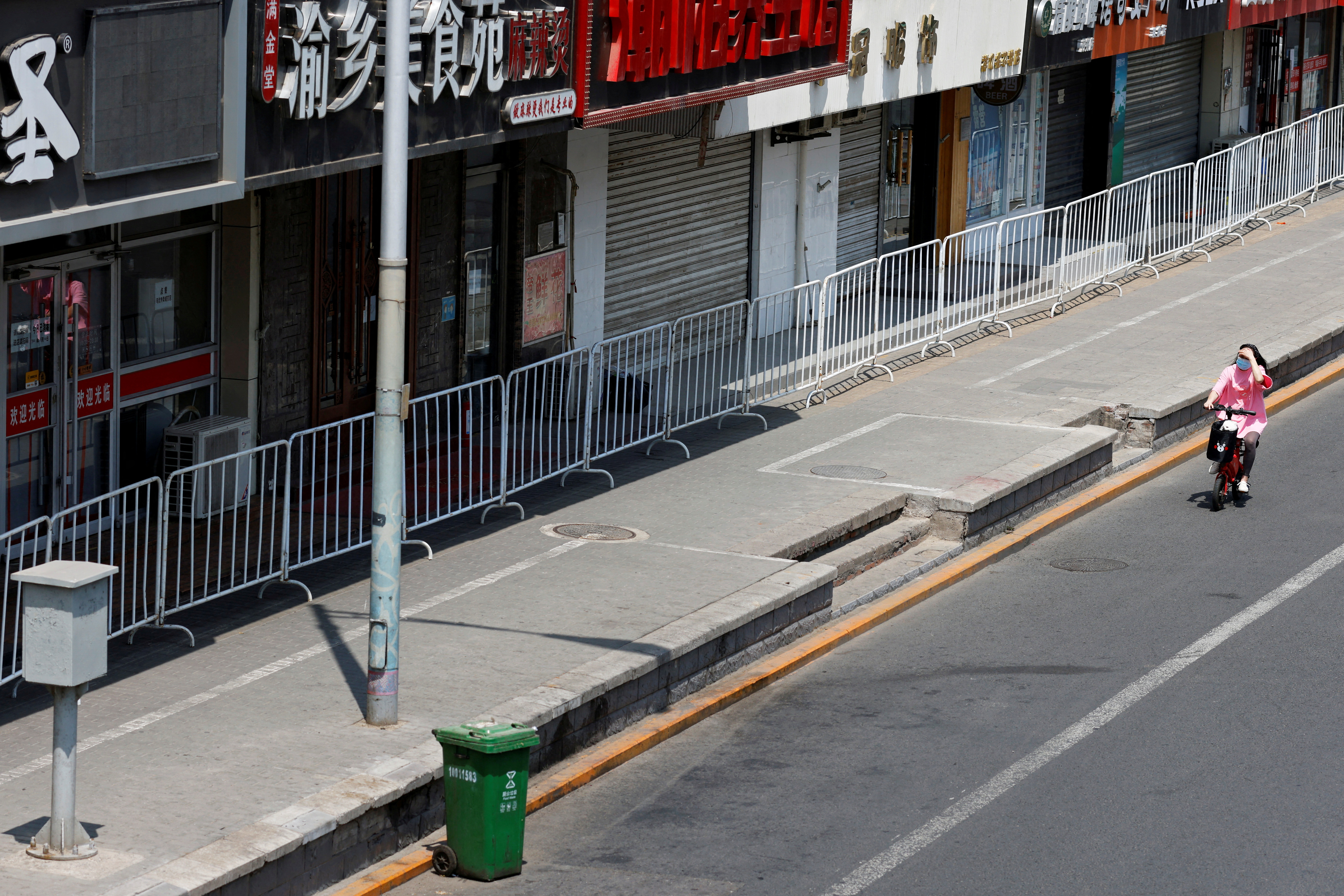 Una mujer pasa junto a tiendas valladas en una calle, en medio del brote de la enfermedad del coronavirus (COVID-19) en Beijing, China 17 de mayo de 2022. REUTERS/Carlos García Rawlins