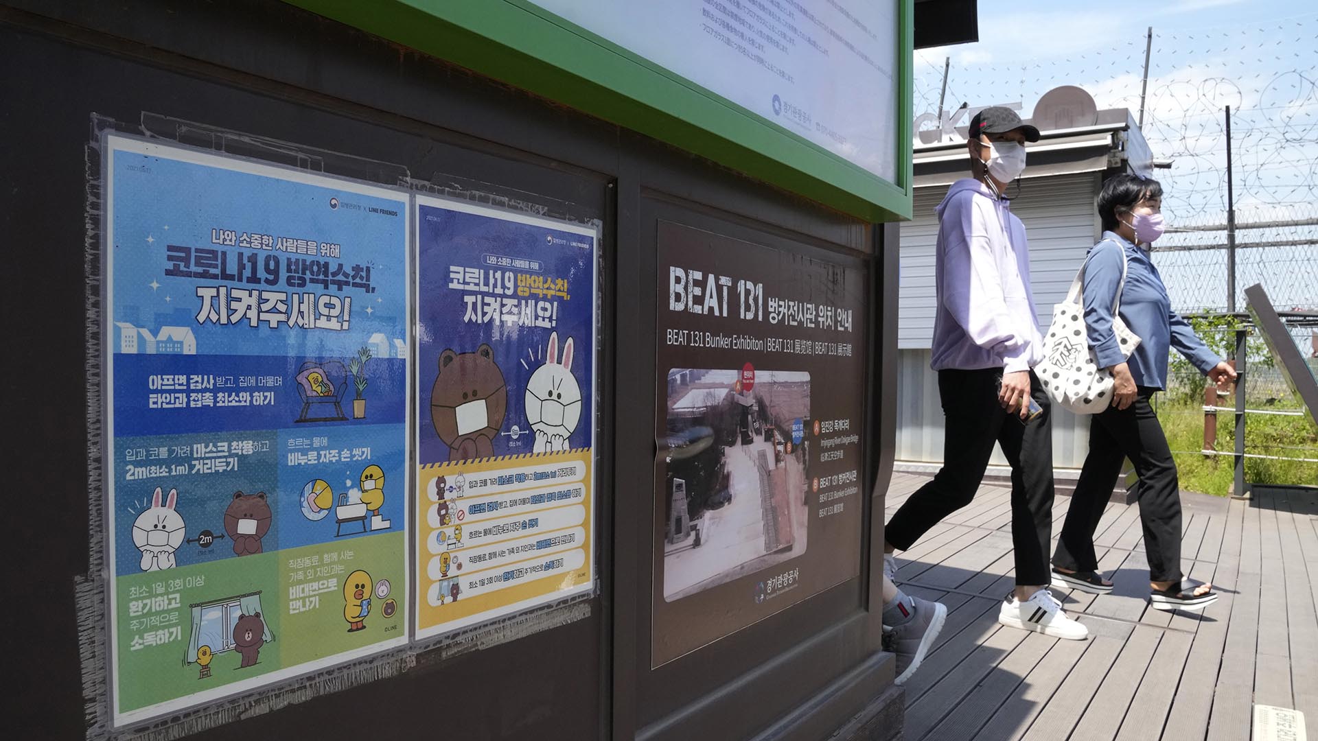 La gente pasa junto a carteles que recuerdan las precauciones contra el coronavirus en el Pabellón Imjingak en Paju, Corea del Sur, cerca de la frontera con el Norte (Foto AP/Ahn Young-joon)