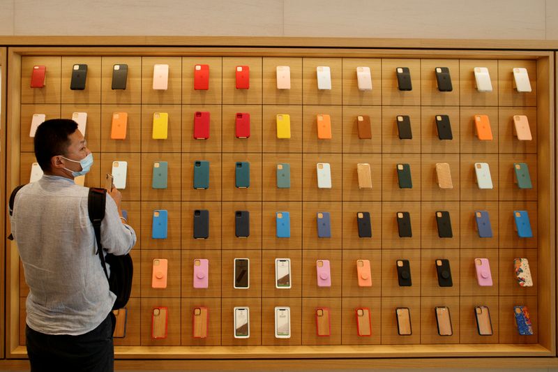 Un hombre parado frente a una pared con carcasas para iPhone en una tienda de Apple (Foto: REUTERS/Thomas Peter)