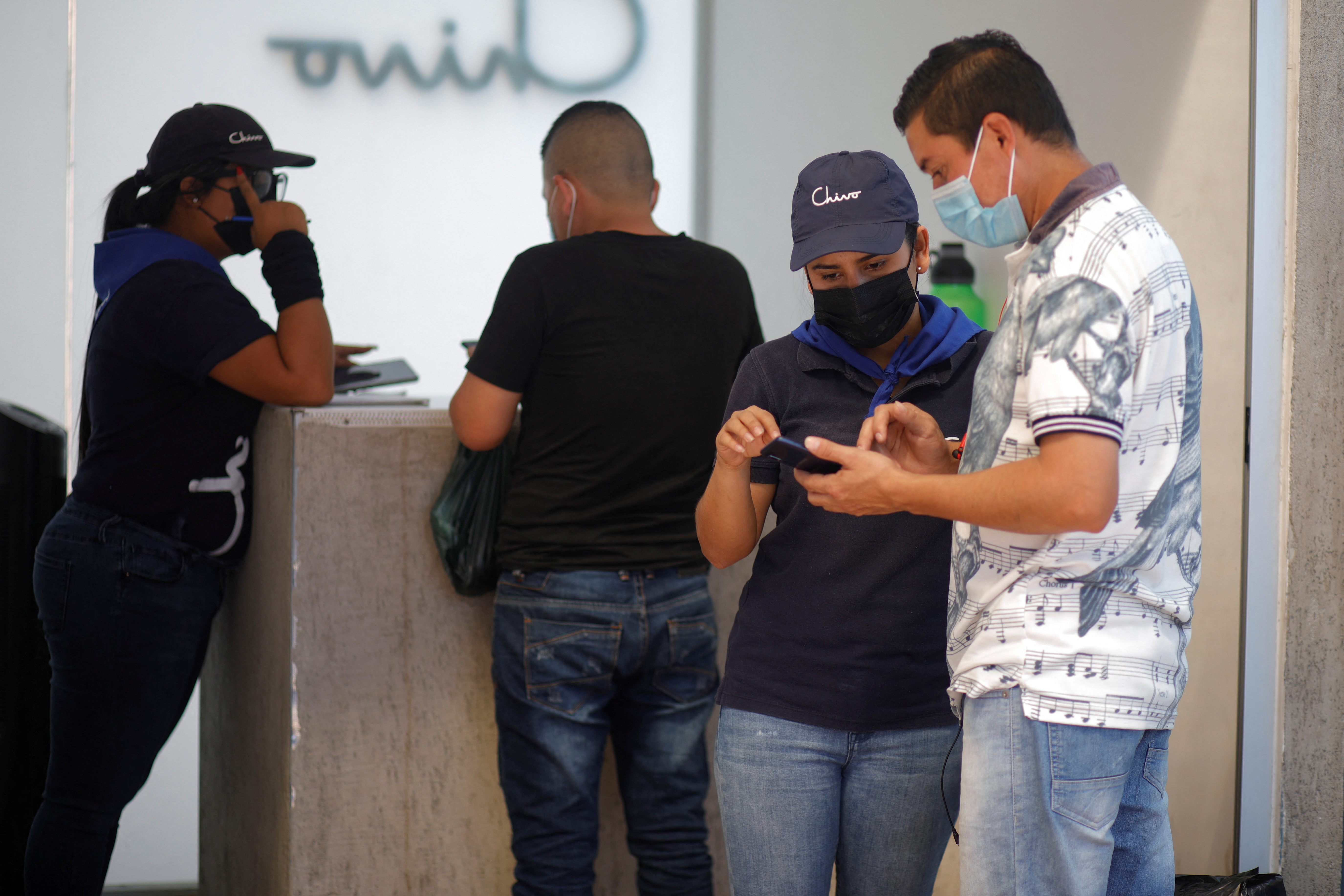 Un trabajador contratado por el gobierno de El Salvador orienta a un cliente interesado en el uso de la Chivo Wallet, la aplicación virtual financiada por el gobierno de Nayib Bukele para transar con Bitcoin, Febrero 1, 2022. REUTERS/Jose Cabezas