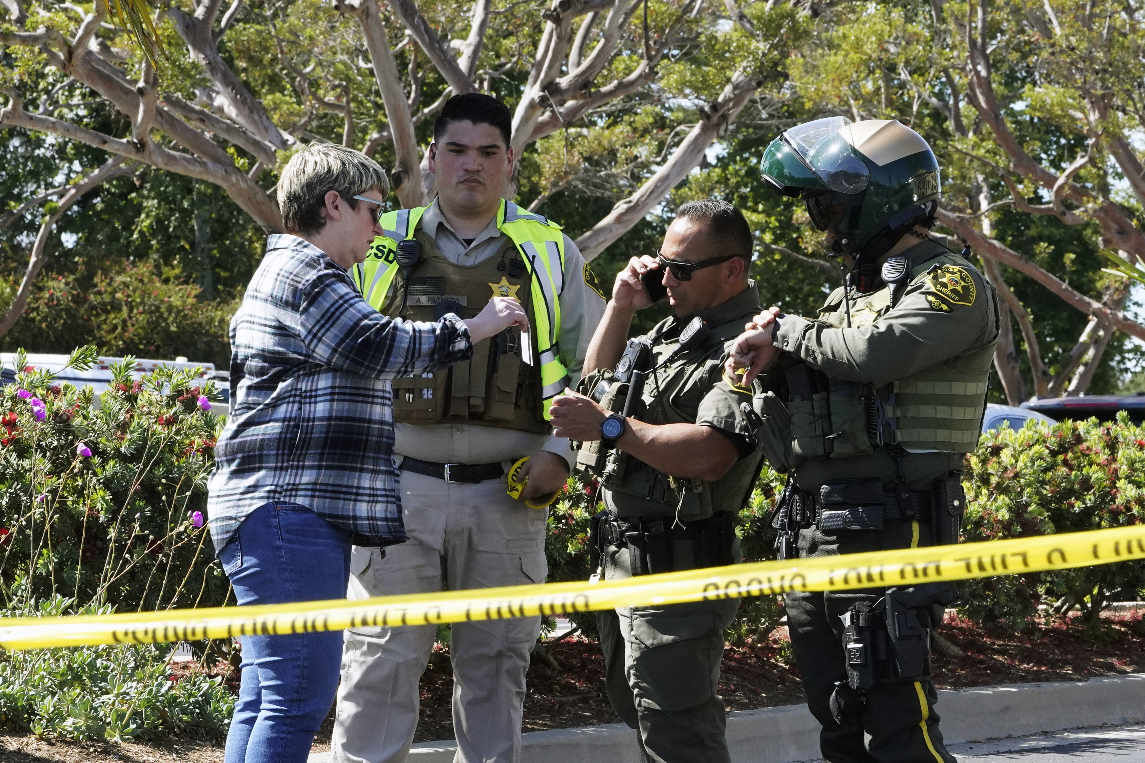 Agentes del alguacil del condado de Orange verifican la identificación de una persona que intenta acceder a un estacionamiento de la Iglesia luego del tiroteo fatal (Foto AP/Damián Dovarganes)