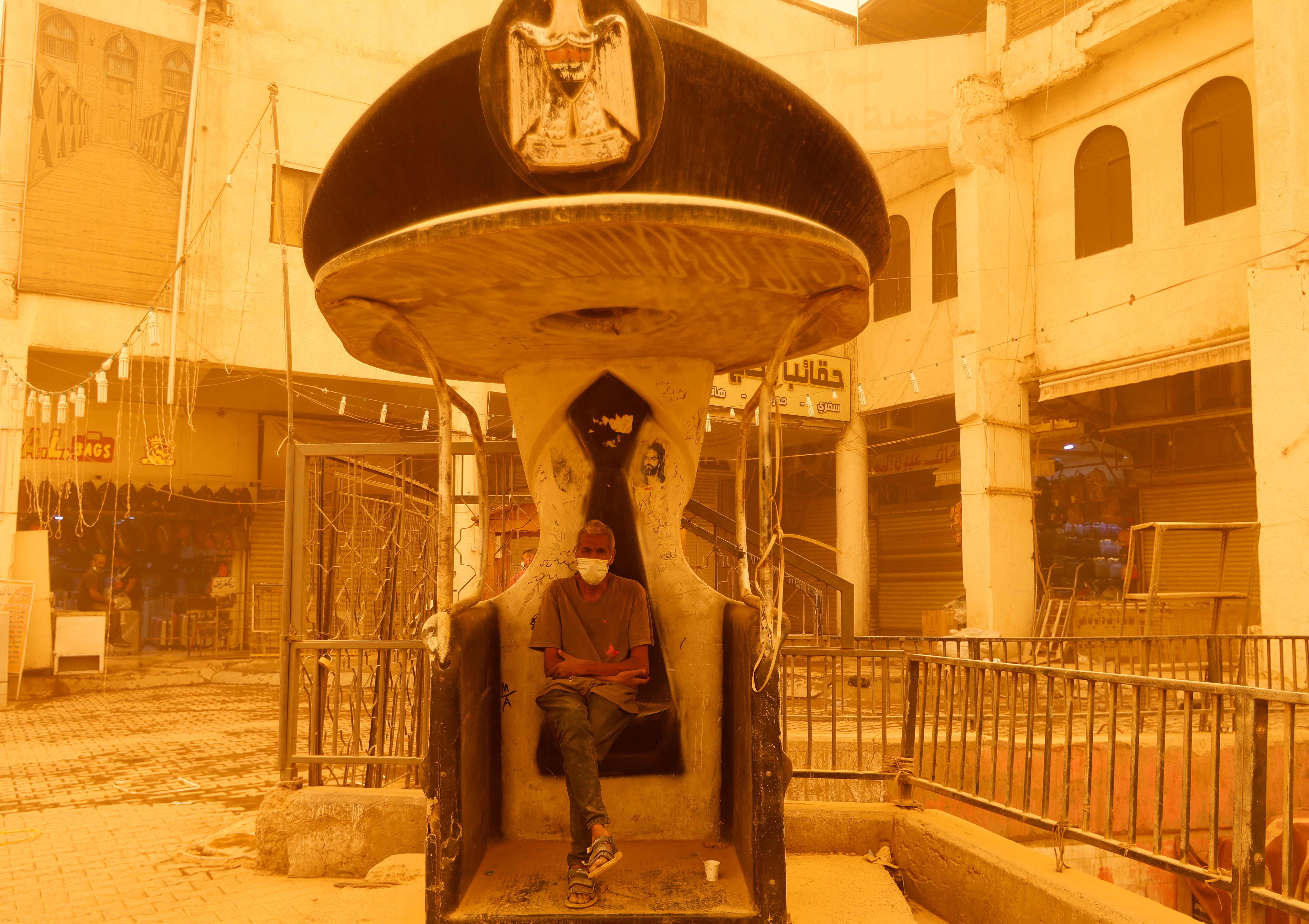 Un hombre usa una máscara mientras descansa en la cabina de un policía de tránsito durante una tormenta de arena en Bagdad, Irak, el 16 de mayo de 2022. REUTERS/Ahmed Saad